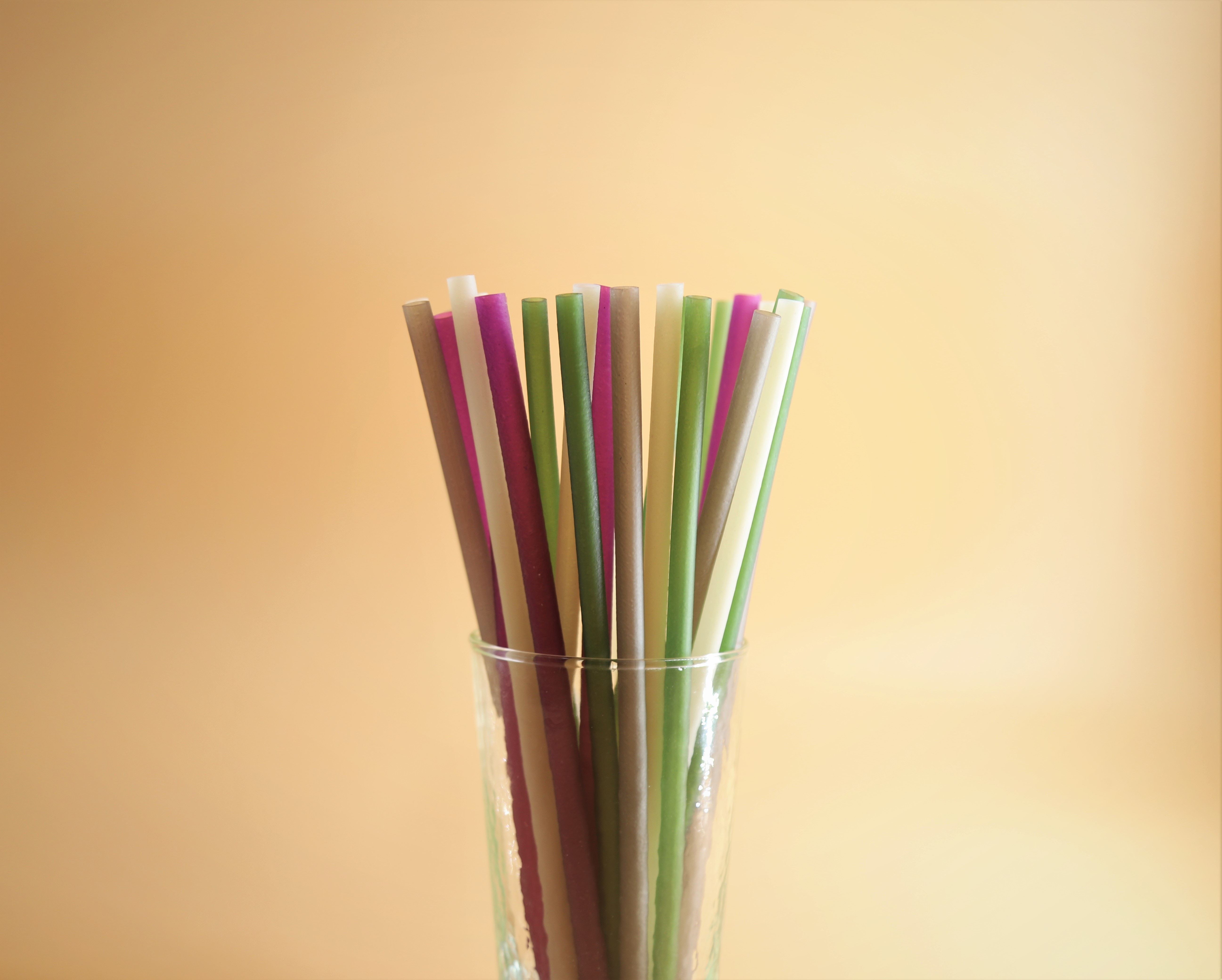 Colorful straws in a cup with a light yellow background